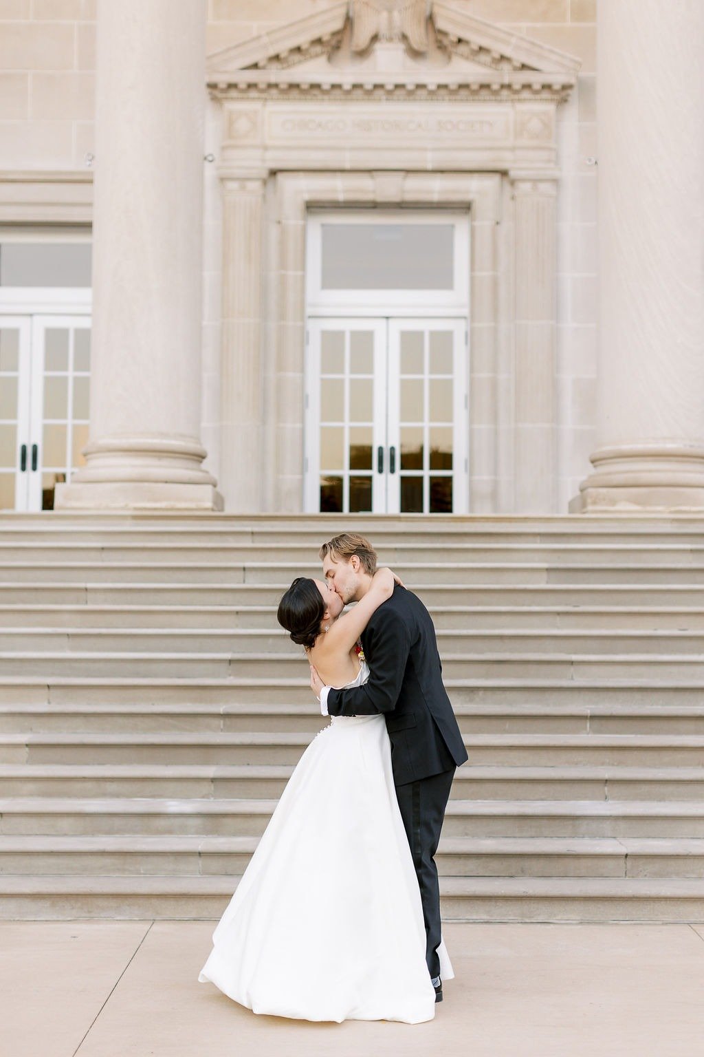Newlyweds kissing on grand steps at a historic venue while planning a wedding in Chicago