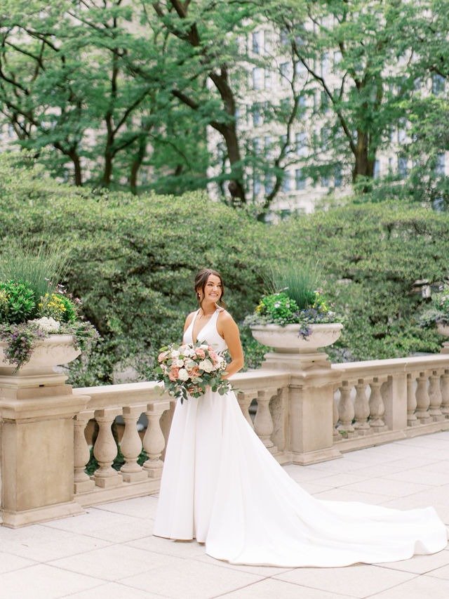 Bride holding bouquet on a terrace surrounded by greenery due to planning a wedding in Chicago