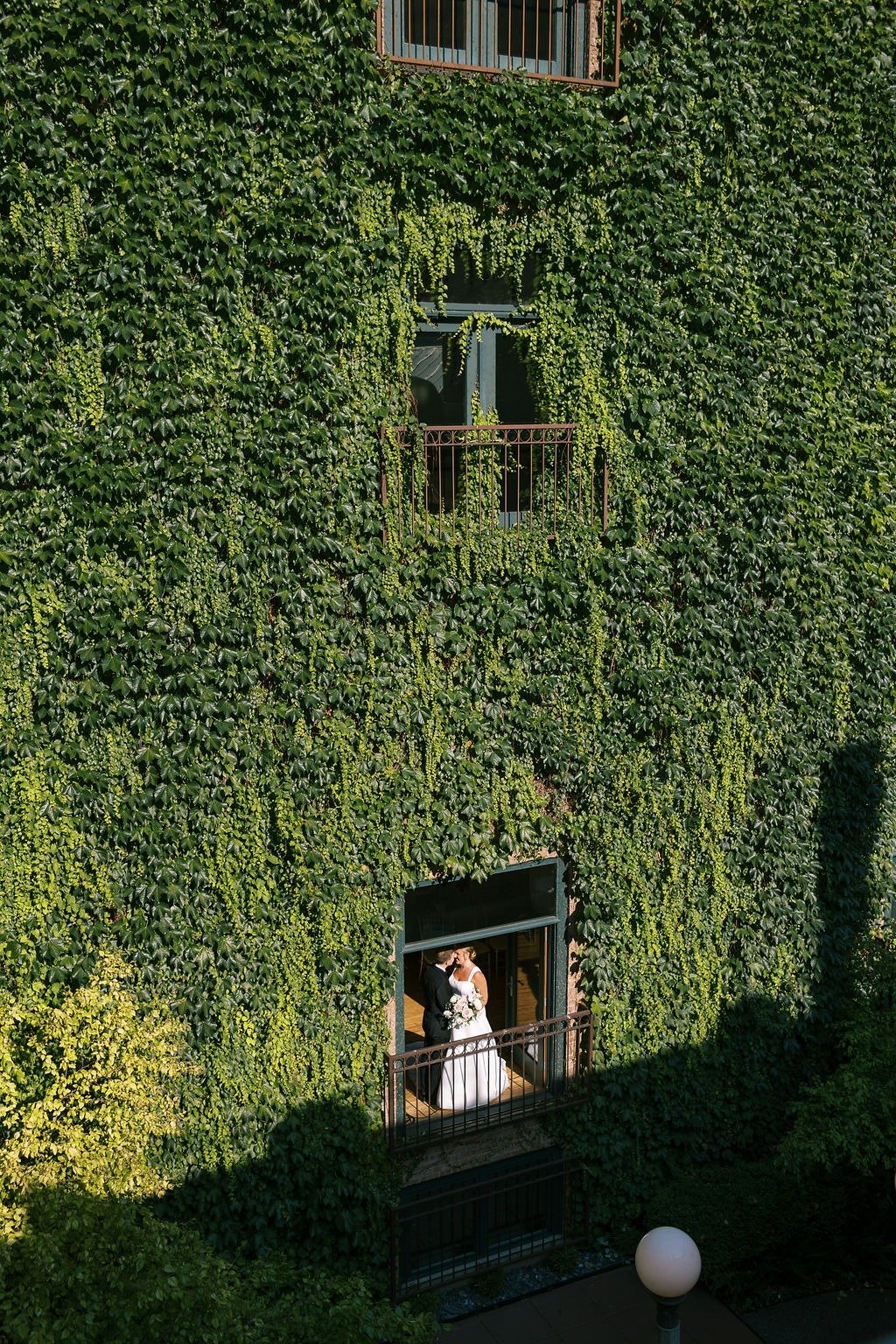 Couple sharing a kiss on a balcony covered in ivy at one of the best places to get married in Chicago