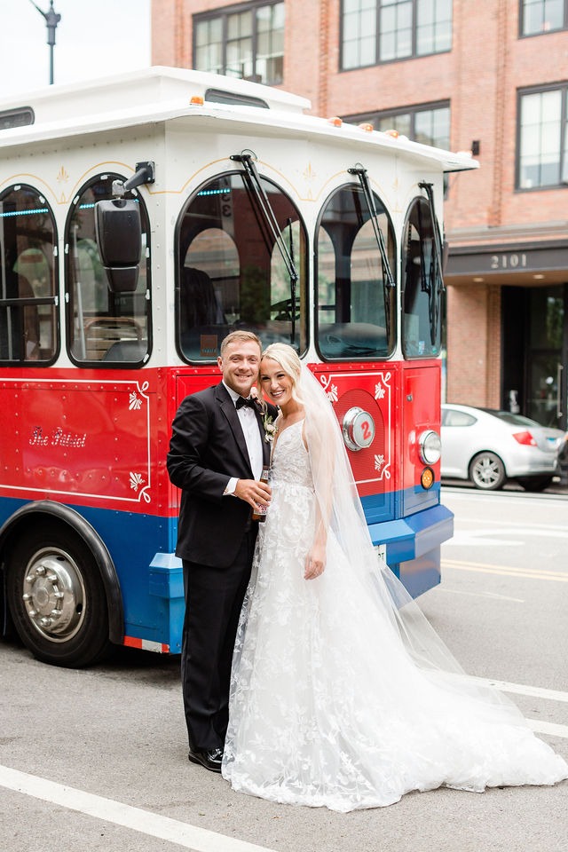 Bride and groom posing by a vintage trolley in the city near wedding venues in downtown Chicago