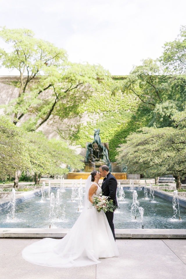 Bride and groom kissing by a fountain in a scenic park near wedding venues in Chicago