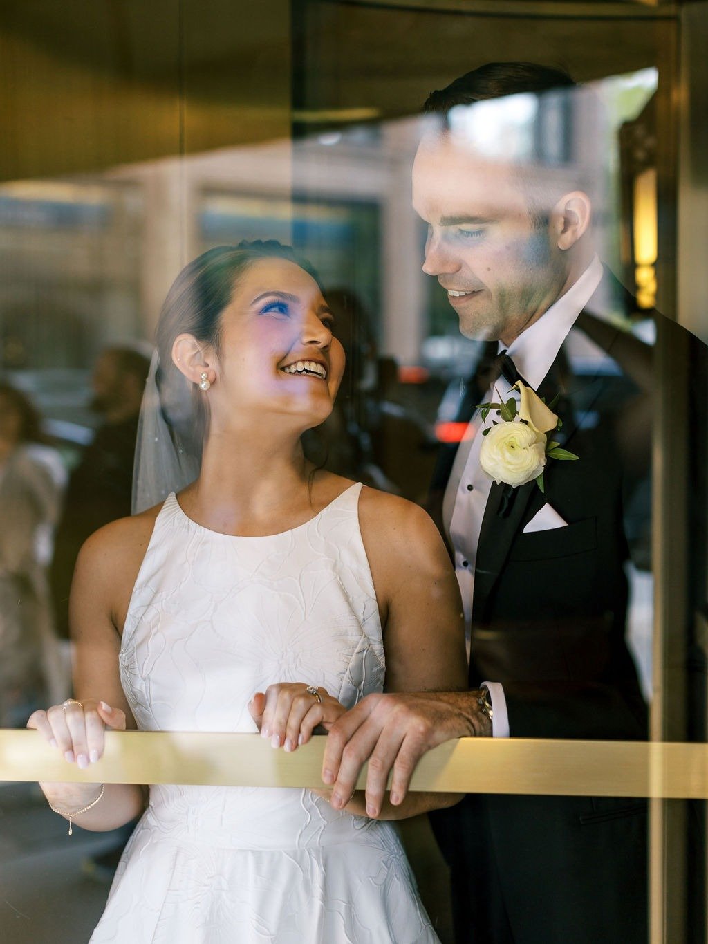 Bride and groom smiling together through a window at a wedding reception venue in Chicago