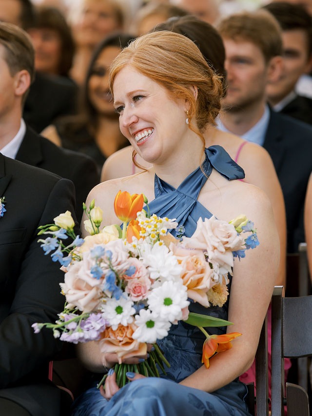 bridesmaid holding a bouquet and smiling during the ceremony at one of the best outdoor wedding venues near chicago